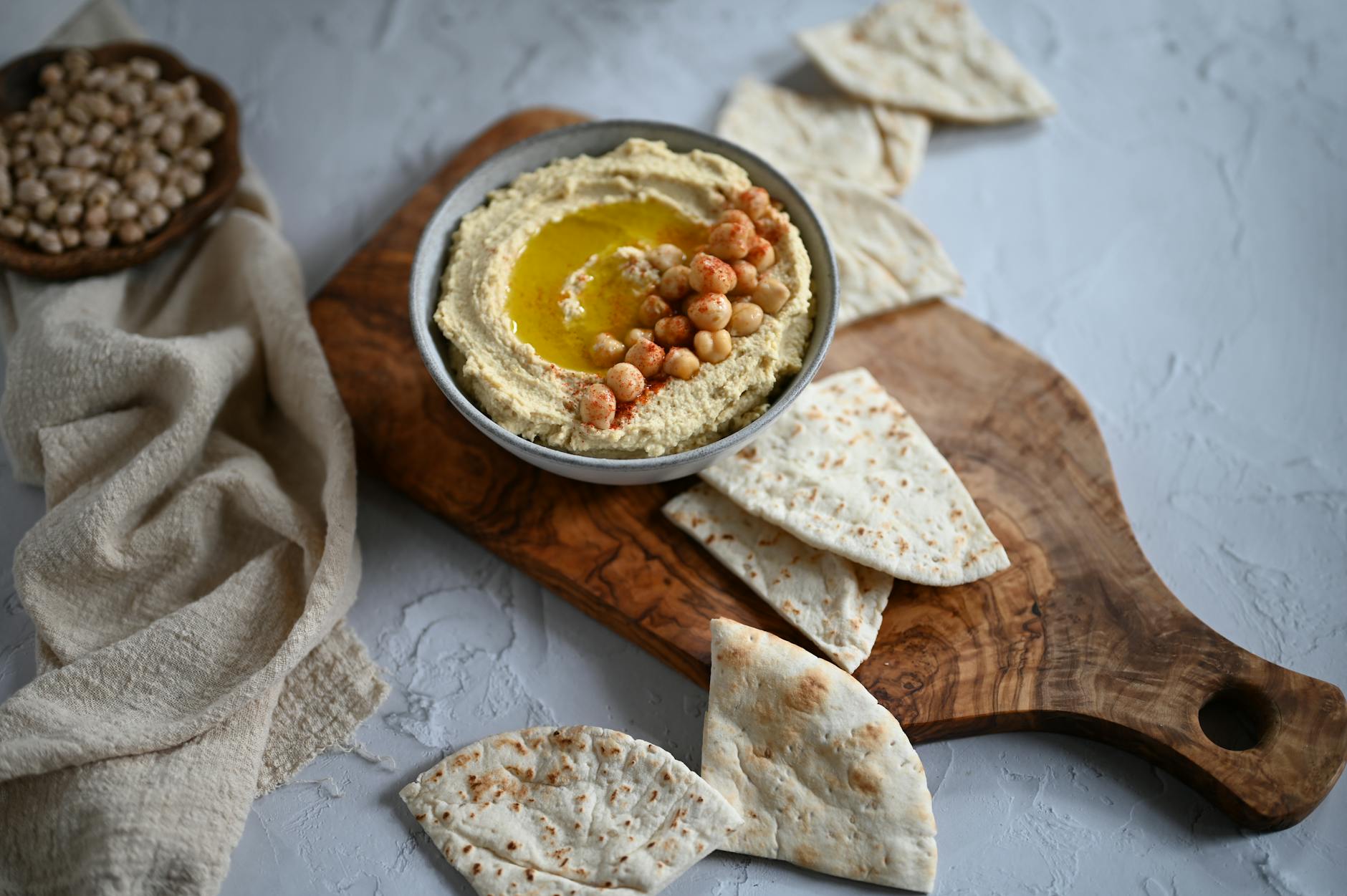 Plate of fresh creamy hummus with whole chickpeas, olive oil, paprika and warm pita - the best hummus in Jerusalem