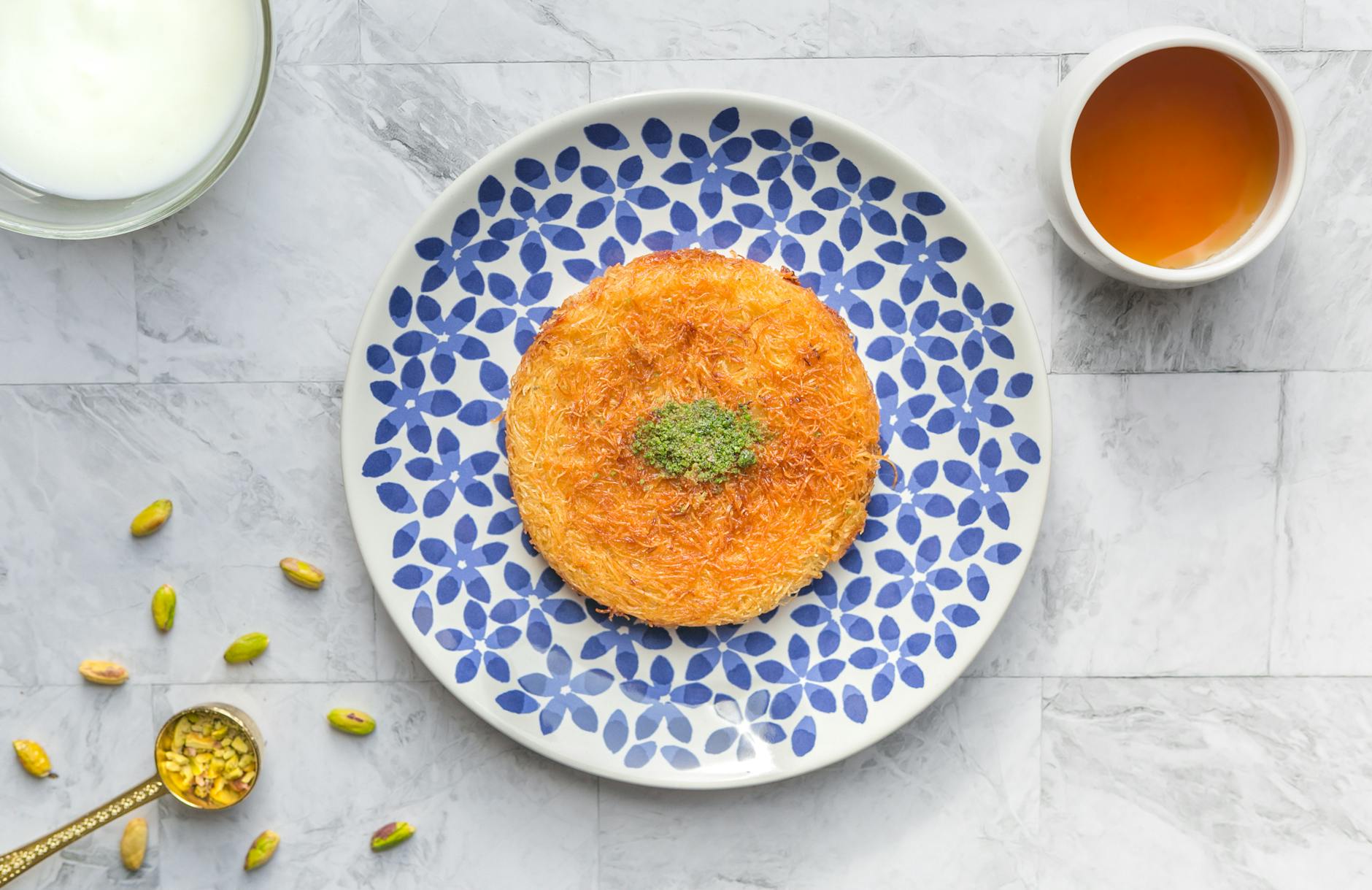 Warm kunafeh dessert with stretchy cheese and pistachio garnish