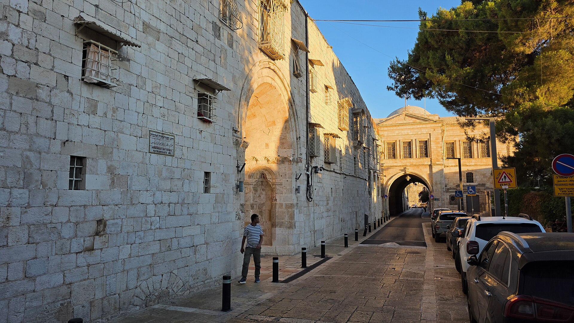 Armenian Orthodox Patriarchate Road in Jerusalem's Armenian Quarter, a quiet lane between tall limestone walls leading to an arched passage in evening sunlight