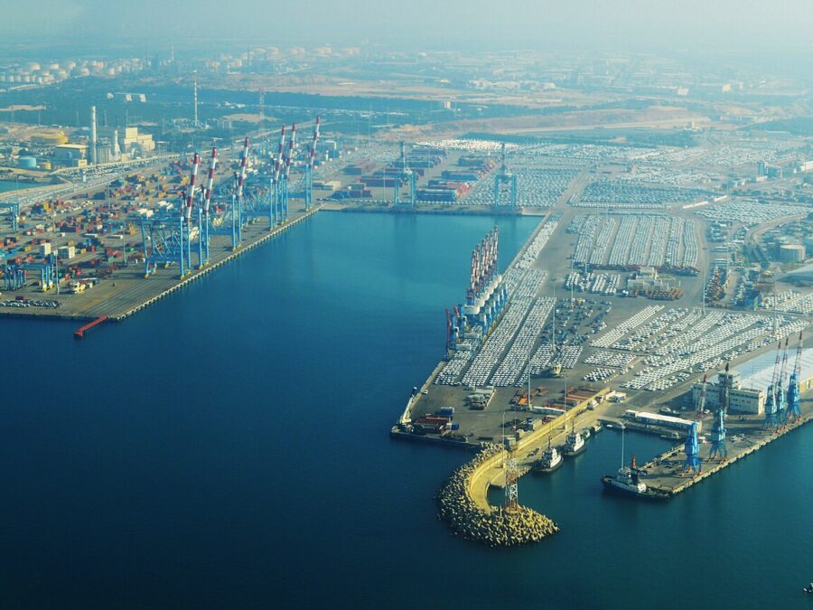 Aerial view of Ashdod Port with container cranes, rows of imported cars and a white cruise ship berthed at the far quay