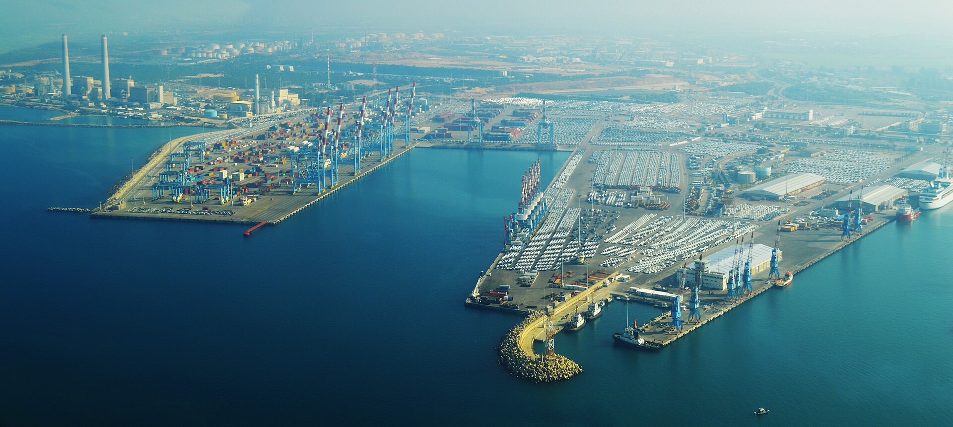 Aerial view of Ashdod Port with container cranes, rows of imported cars and a white cruise ship berthed at the far quay