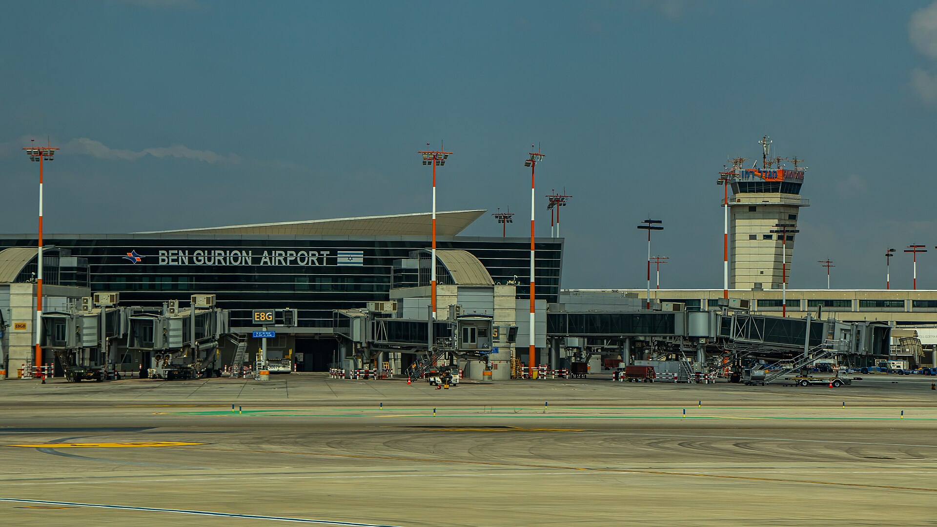 Ben Gurion Airport's Terminal 3 seen across the apron, with Ben Gurion Airport lettering on the facade, jet bridges, floodlight masts and the control tower