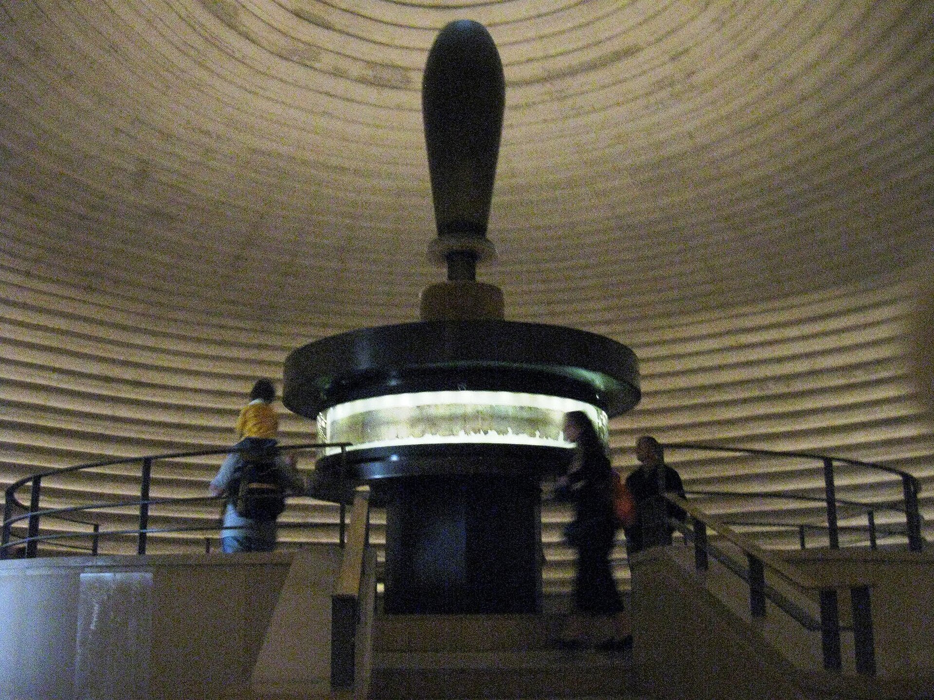 Central display inside the Shrine of the Book, a lit drum-shaped case crowned by a giant scroll handle beneath the ribbed dome, with visitors circling a railing