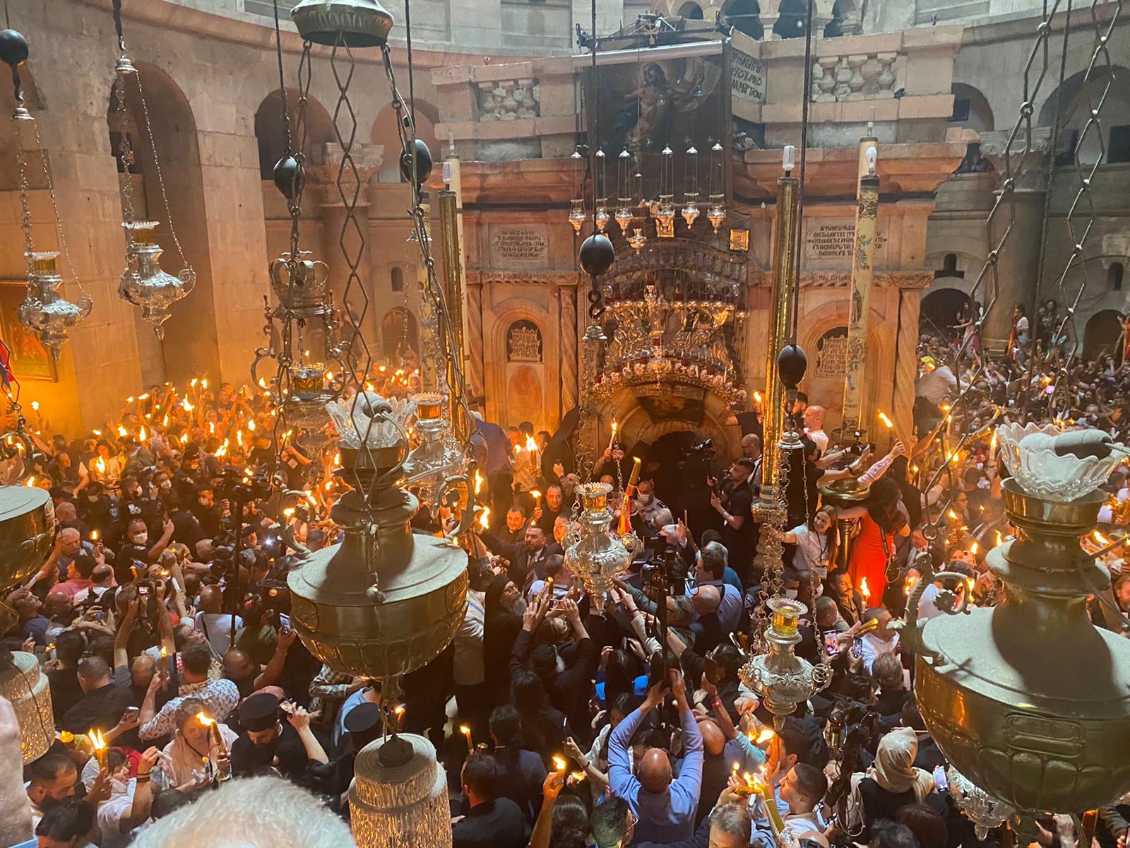 Crowd in the Rotunda of the Church of the Holy Sepulchre holding up lit candles in front of the Aedicule during the Holy Fire ceremony, seen from the gallery