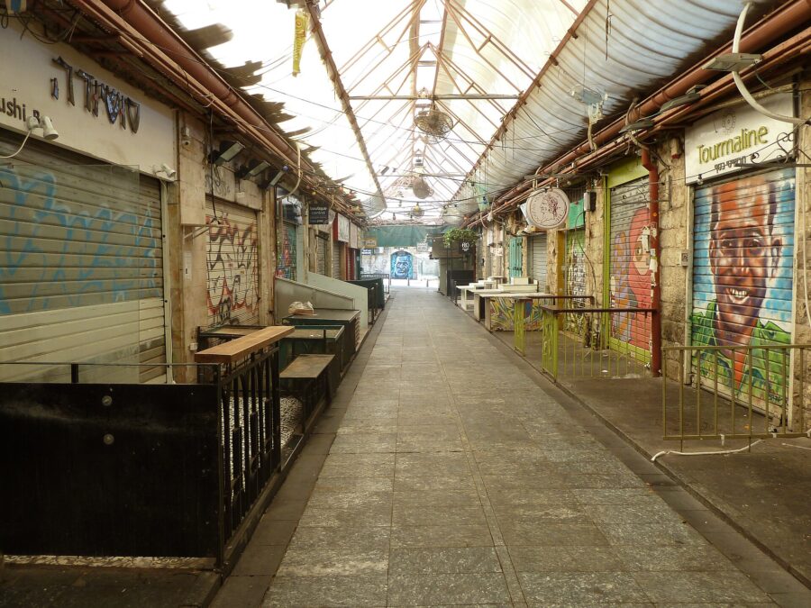 A deserted covered lane of Mahane Yehuda market in Jerusalem on a Saturday morning, every stall shuttered and several shutters painted with murals