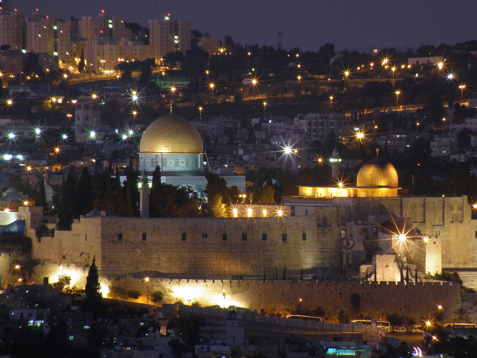 The Dome of the Rock and the dome of Al-Aqsa Mosque lit up at dusk above the floodlit southern wall of the Temple Mount, seen from the Haas Promenade