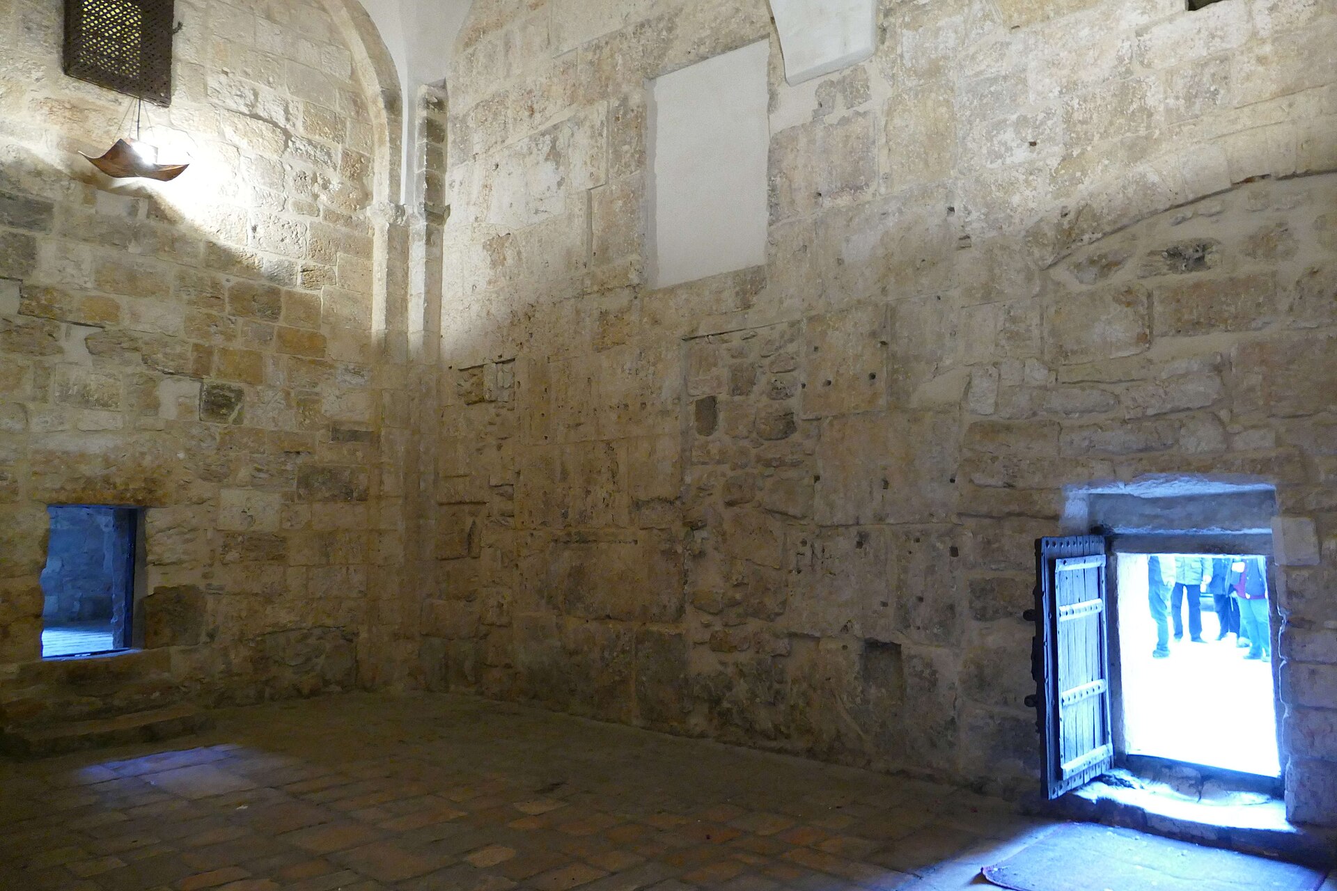 Inside the stone narthex of the Church of the Nativity, looking toward the very low Door of Humility with daylight and visitors visible outside