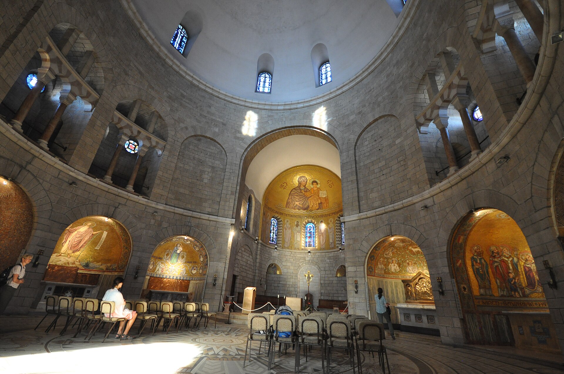 The circular interior of the Dormition Abbey church with golden mosaics of saints and the Virgin and Child in arched side chapels
