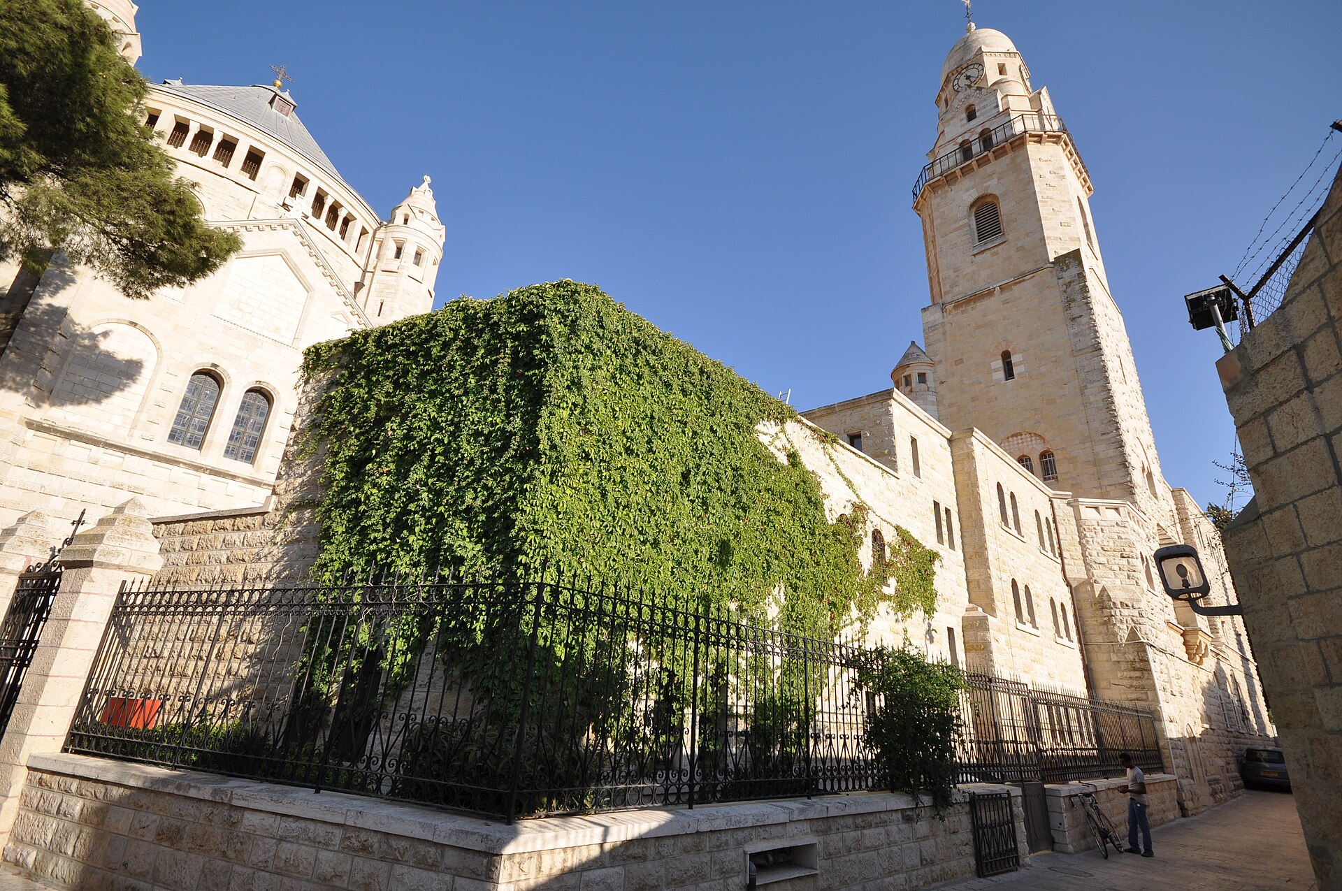The Dormition Abbey on Mount Zion with its round church, bell tower and ivy-covered wall under a clear blue sky