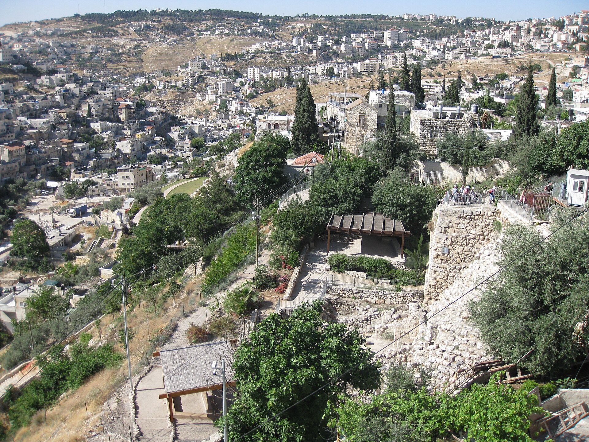 Elevated view over the City of David archaeological park, with paths, shade pergolas and a railed viewing platform on the slope above the Kidron Valley
