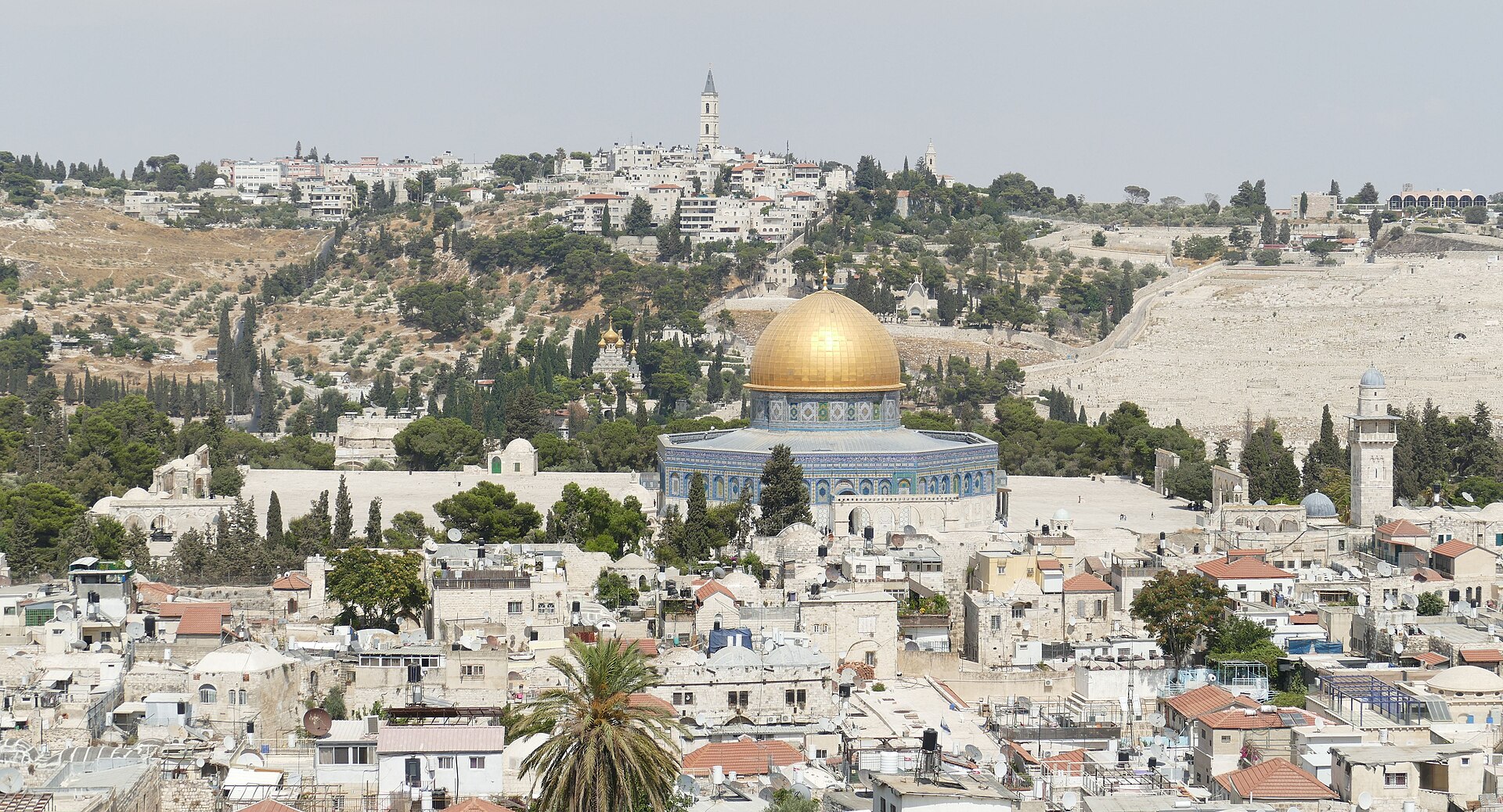 The golden Dome of the Rock and the Mount of Olives seen from the Church of the Redeemer bell tower, above the crowded rooftops of Jerusalem's Old City