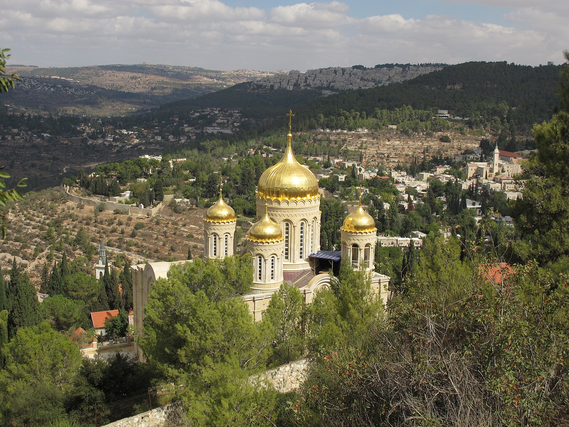 Golden onion domes of the Russian Orthodox Gorny Convent above Ein Karem, with the bell tower of St John the Baptist church in the village and wooded terraced hills beyond