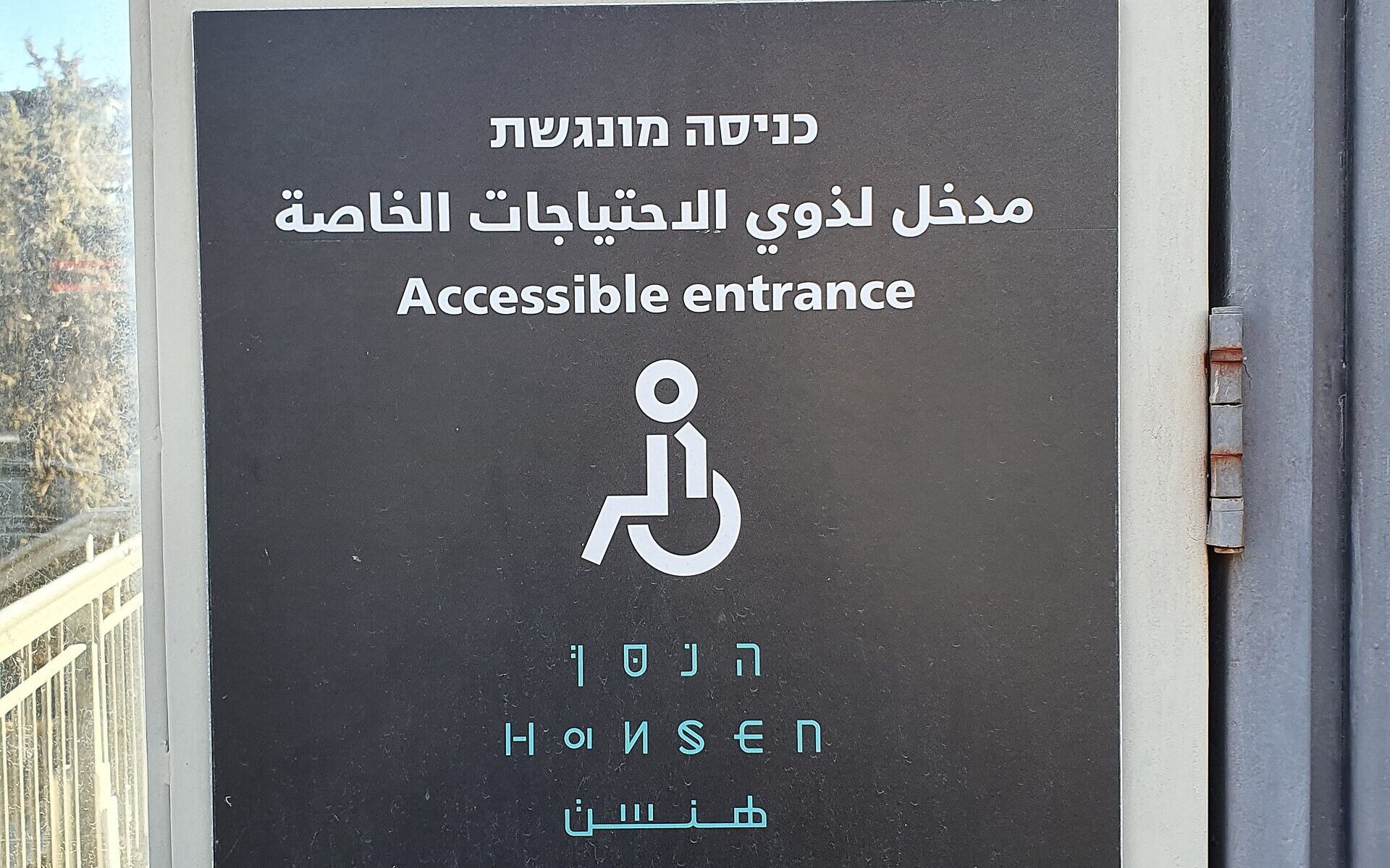 A Hebrew, Arabic and English 'Accessible entrance' sign with a wheelchair symbol at Hansen House in Jerusalem