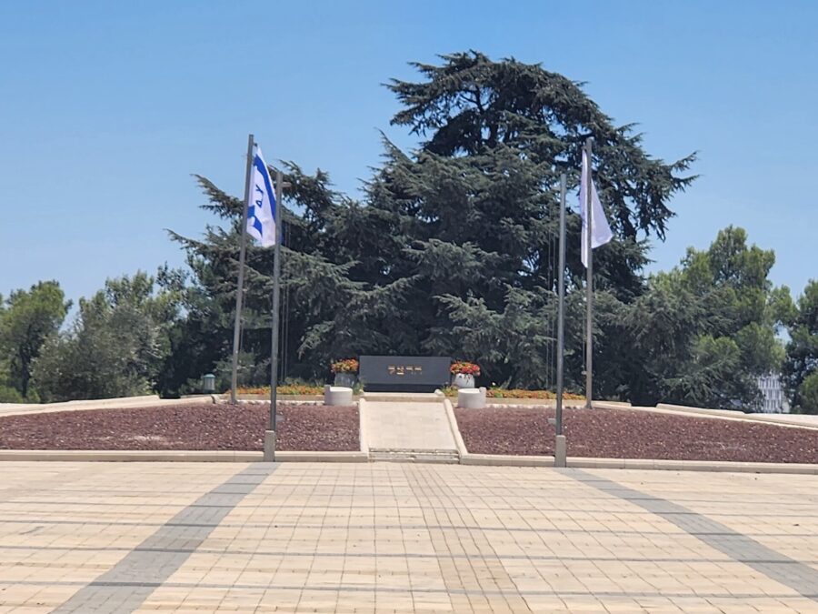 Theodor Herzl's tomb at the head of the paved ceremonial plaza on Mount Herzl, with Israeli flags and a large cedar behind