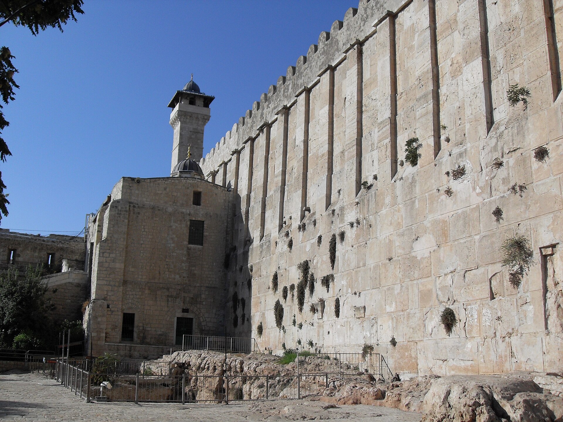 Huge Herodian stone blocks and pilasters along the wall of the Cave of the Patriarchs, or Ibrahimi Mosque, in Hebron, with a minaret at the far end