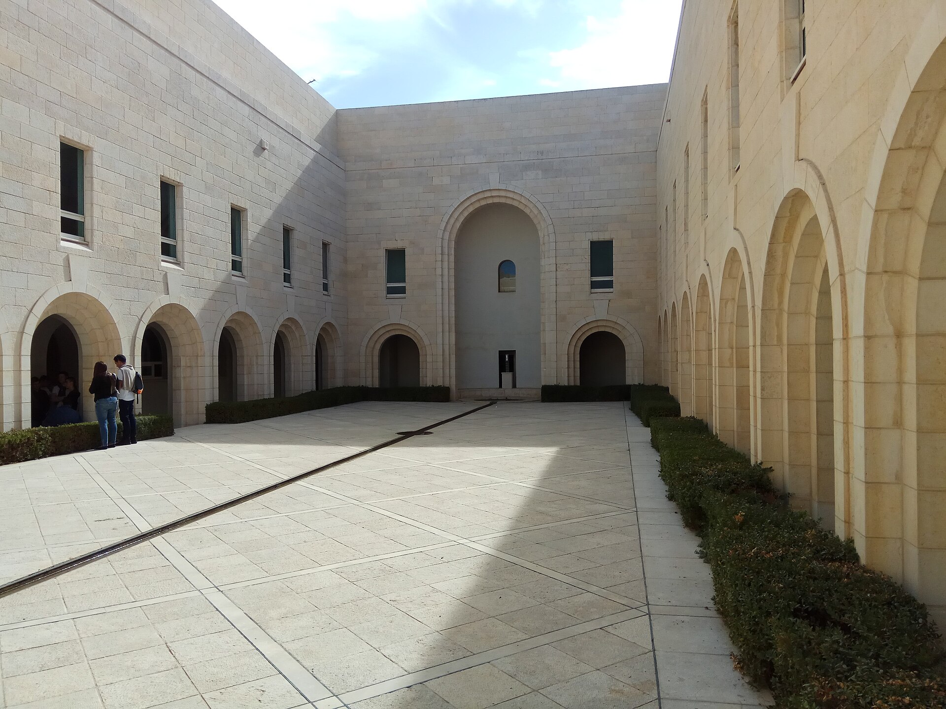 The inner courtyard of Israel's Supreme Court building in Jerusalem, with pale stone walls, arched arcades and a narrow water channel running diagonally across the paving