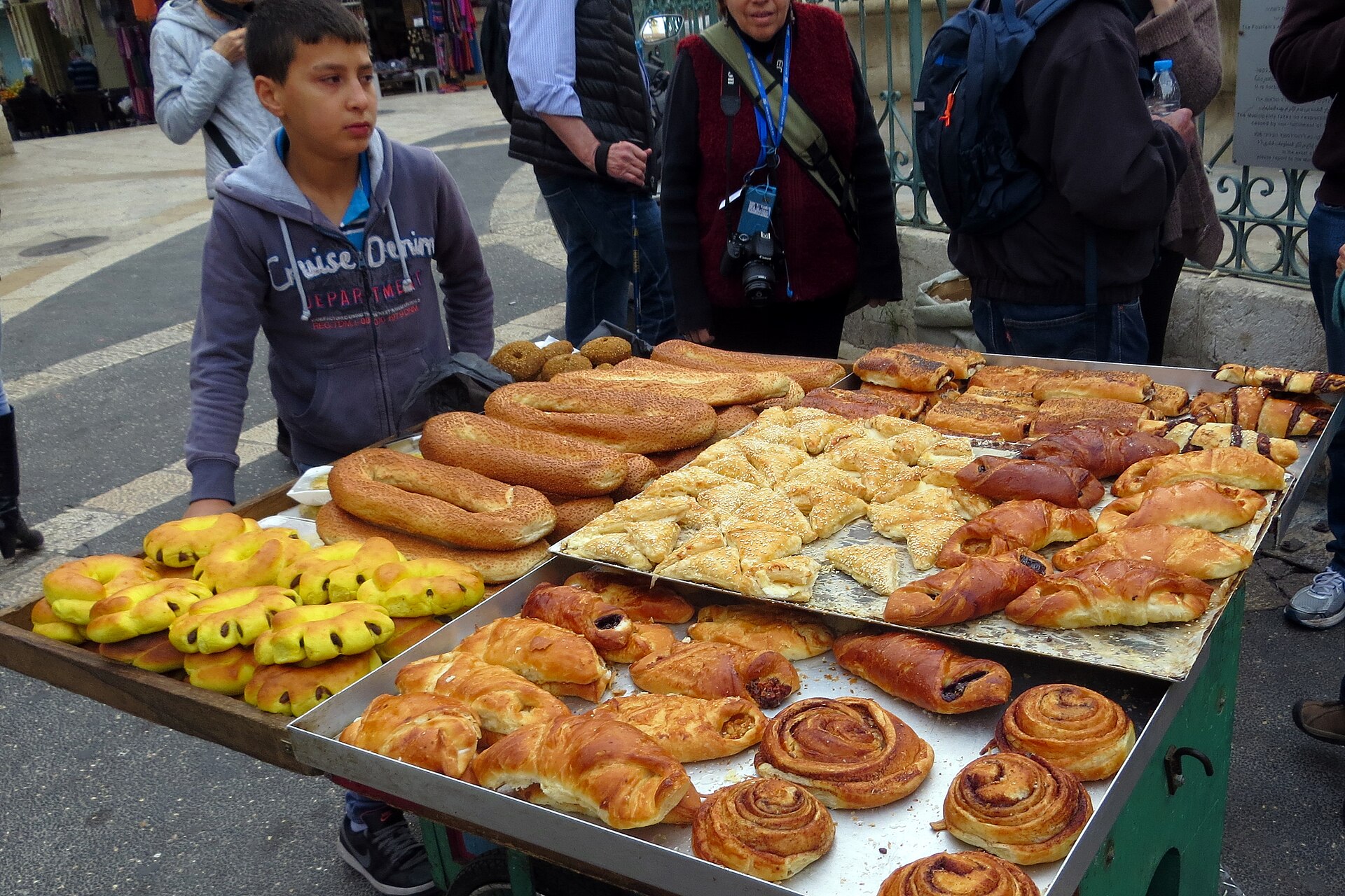A young vendor with a cart of sesame ka'ak bread rings, cinnamon rolls and pastries near the Muristan fountain in Jerusalem's Old City