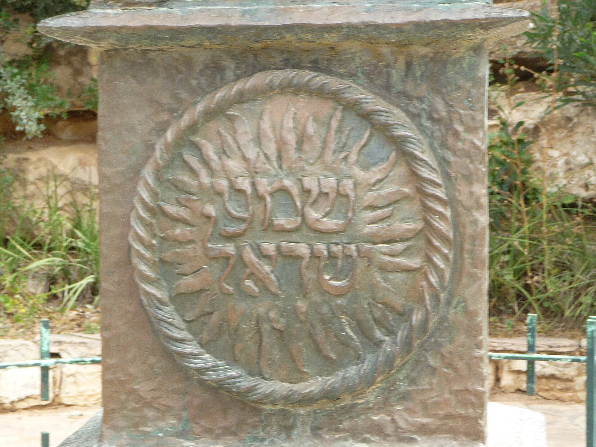 Close-up of a bronze relief panel on the Knesset Menorah, showing the Hebrew words Shema Yisrael inside a rope-edged circle of flames