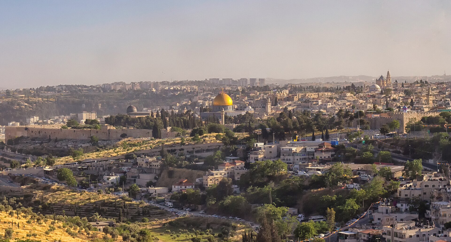 Late-afternoon sun warms Jerusalem's Old City walls, the grey dome of Al-Aqsa Mosque and the golden Dome of the Rock above hillside houses and olive terraces