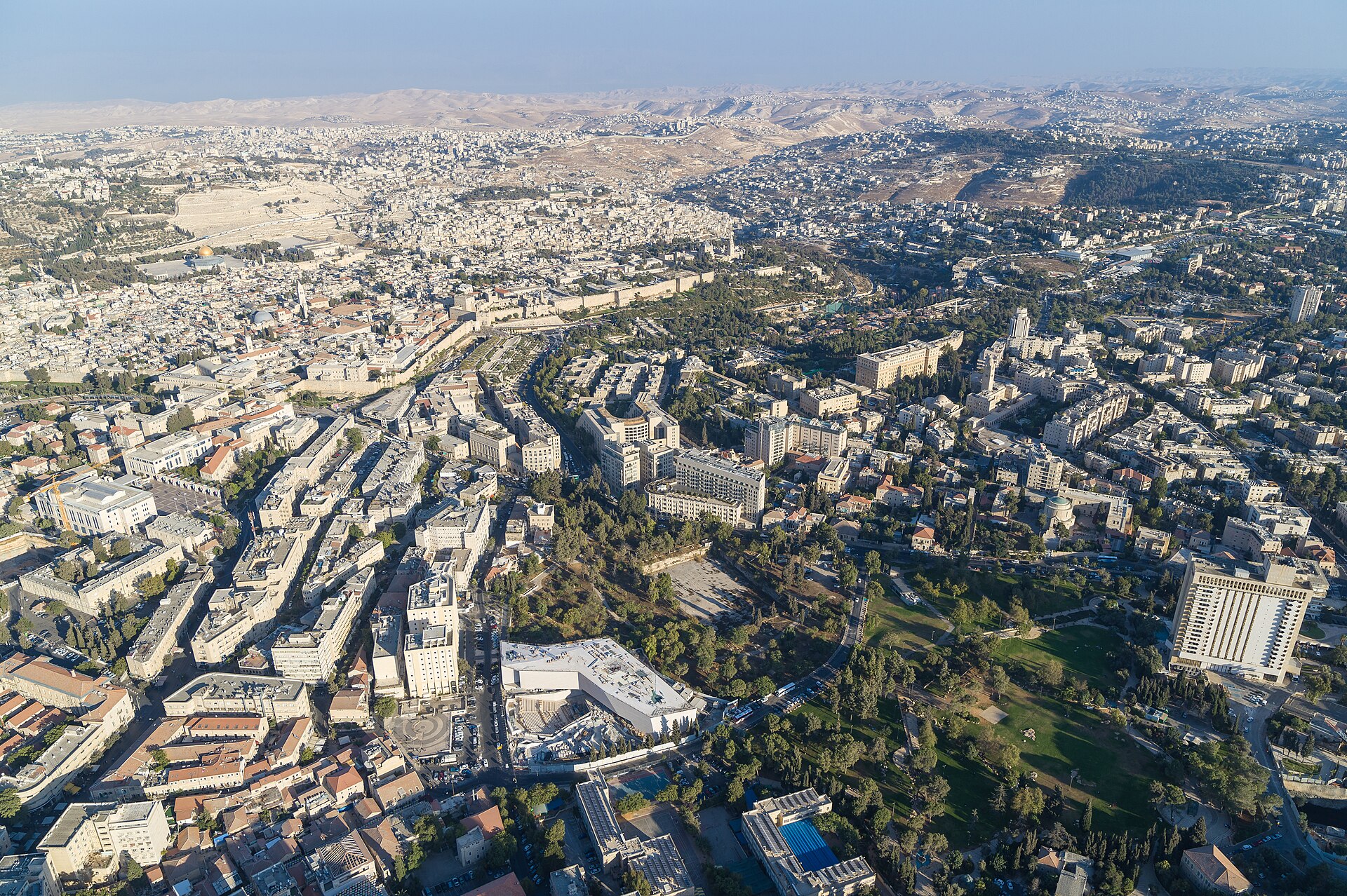 Aerial view of central Jerusalem with the Museum of Tolerance under construction beside the green expanse of Independence Park, the Old City walls and the Dome of the Rock beyond, and the Judean Desert on the horizon