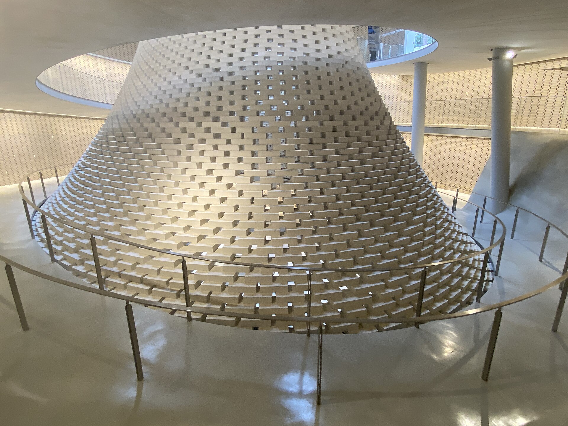 The interior of the National Memorial Hall for Israel's Fallen on Mount Herzl, a tall cone of pale bricks rising towards a skylight, surrounded by a spiral walkway