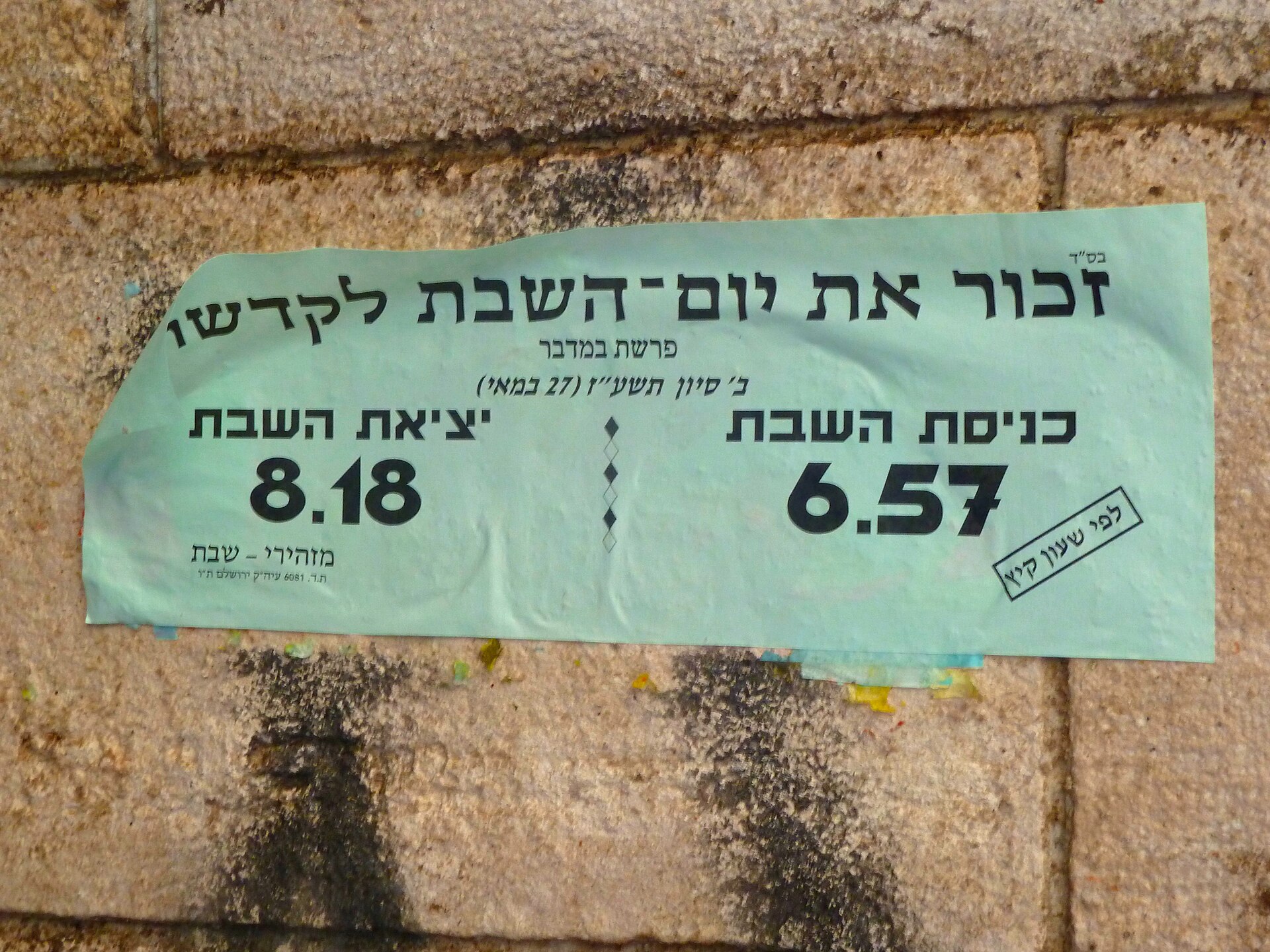 A pale green Hebrew notice on a Jerusalem stone wall giving the times Shabbat begins, 6.57, and ends, 8.18, for 27 May 2017