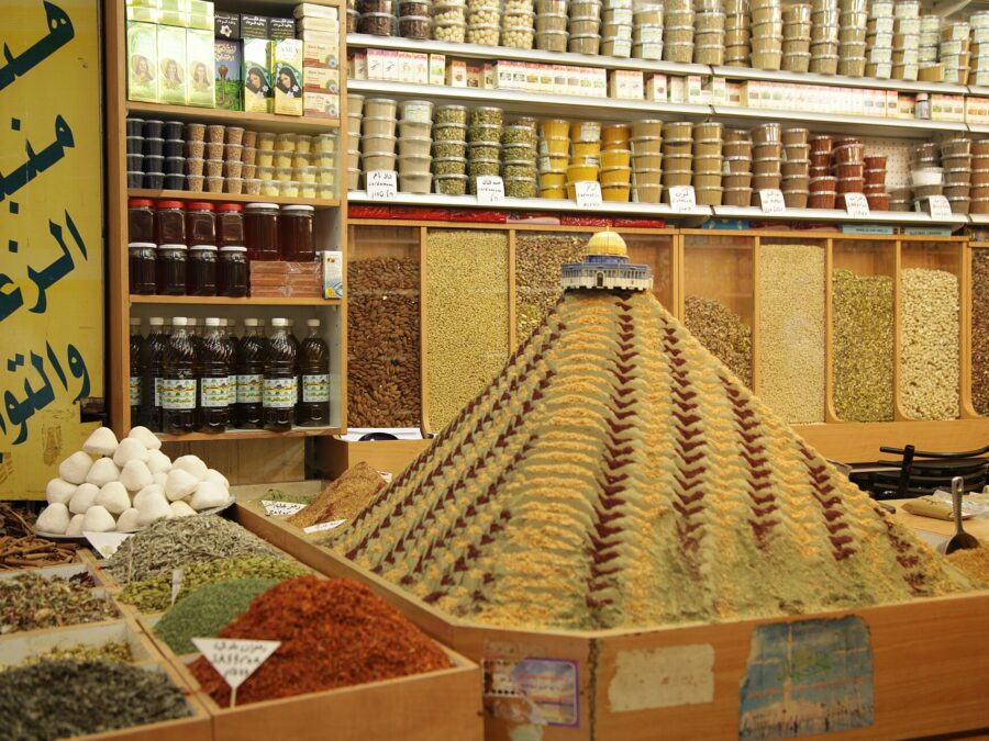 A patterned pyramid of ground spices topped by a model of the Dome of the Rock in an Old City spice shop, with shelves of labelled spice tubs behind