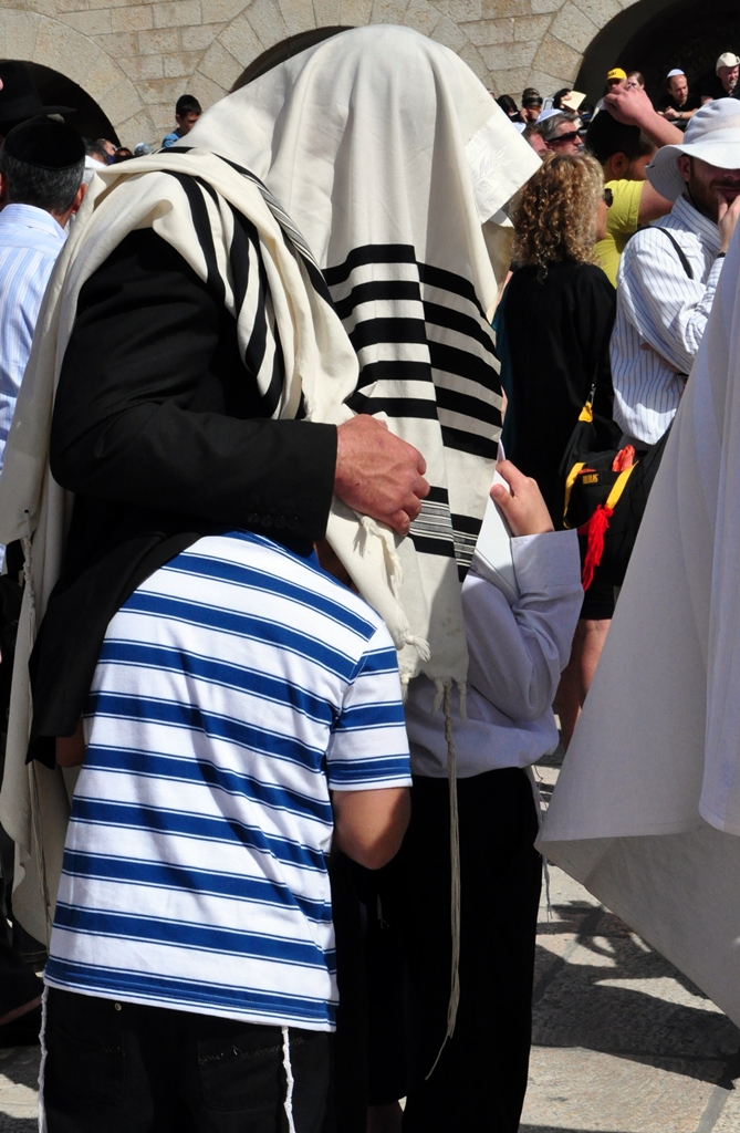 A kohen with a prayer shawl draped over his head and children beneath it during the Priestly Blessing at the Western Wall in Jerusalem