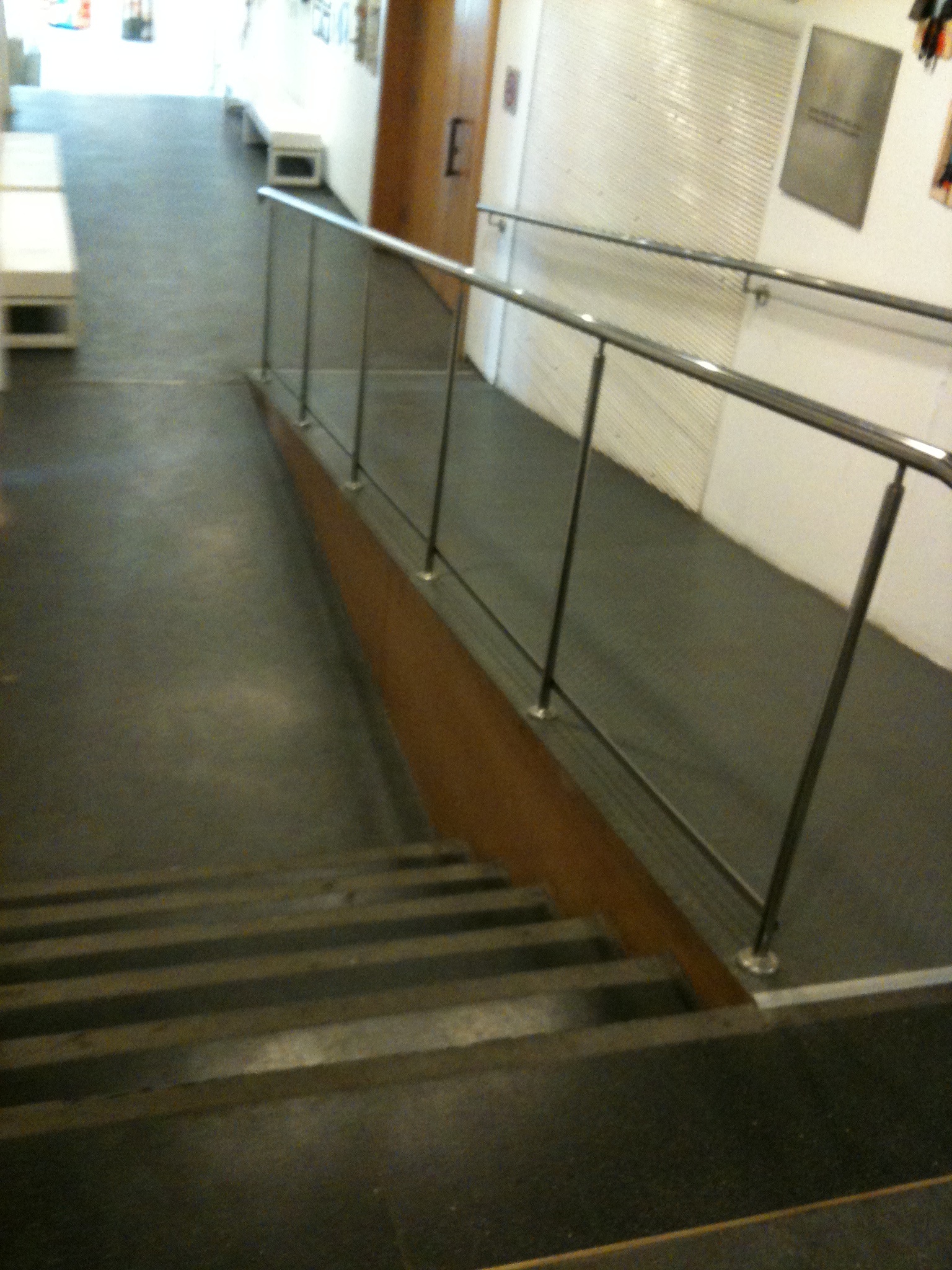 A ramp with a steel handrail running down beside a flight of stairs inside the Israel Museum in Jerusalem