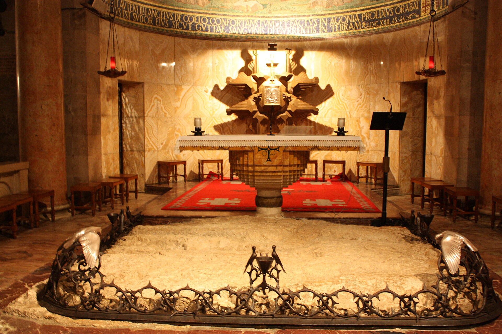 The Rock of Agony inside the Church of All Nations, a patch of bare bedrock ringed by a wrought-iron crown of thorns with doves, in front of the altar