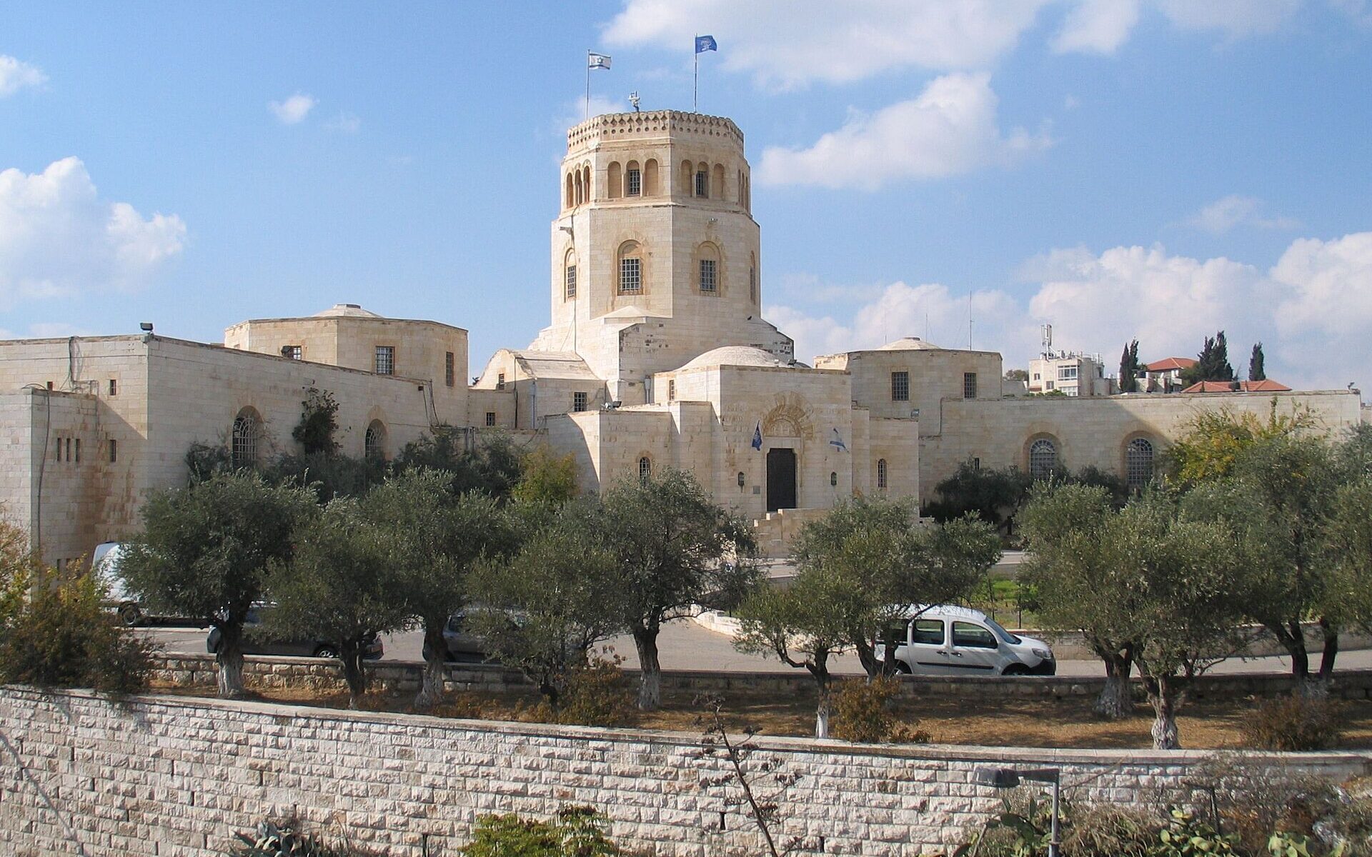 The white limestone Rockefeller Archaeological Museum in Jerusalem with its octagonal tower, seen across olive trees and a stone wall on Sultan Suleiman Street
