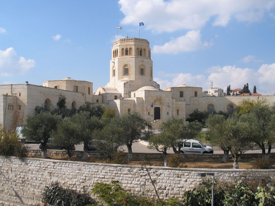 The white limestone Rockefeller Archaeological Museum in Jerusalem with its octagonal tower, seen across olive trees and a stone wall on Sultan Suleiman Street