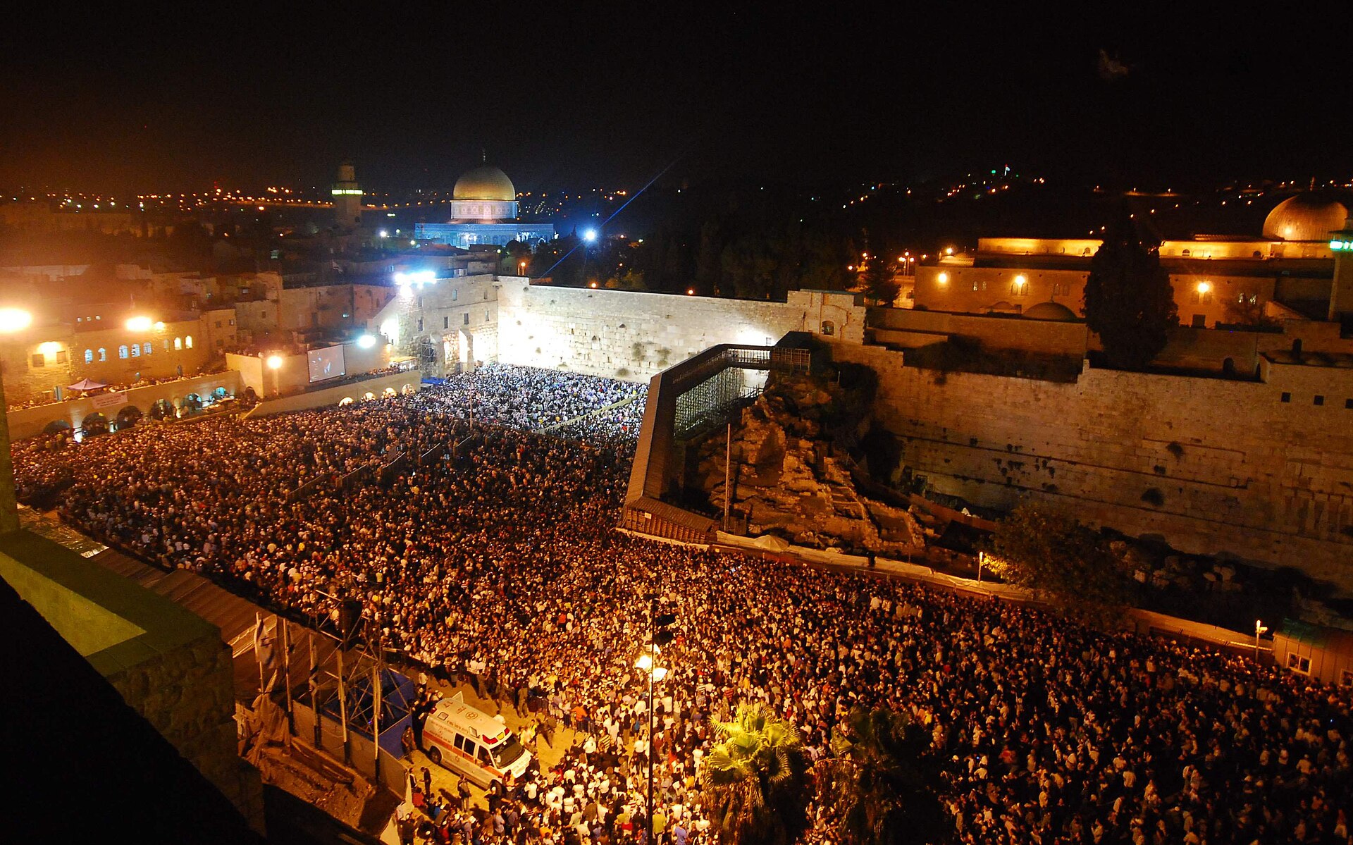 The Western Wall plaza packed with tens of thousands of worshippers at night during Selichot, with the Dome of the Rock lit behind
