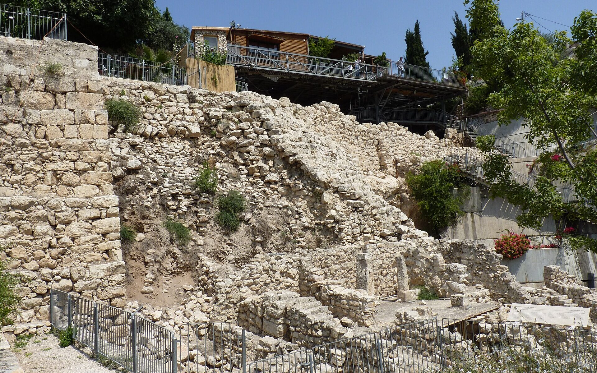 The Stepped Stone Structure in the City of David, a steep terraced stone slope above excavated Iron Age house walls and pillars, with a viewing deck above