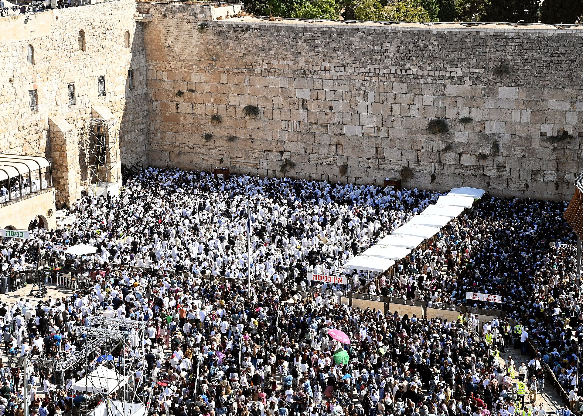 Thousands of worshippers, most of the men wrapped in white prayer shawls, fill the Western Wall plaza for the mass Priestly Blessing during Sukkot