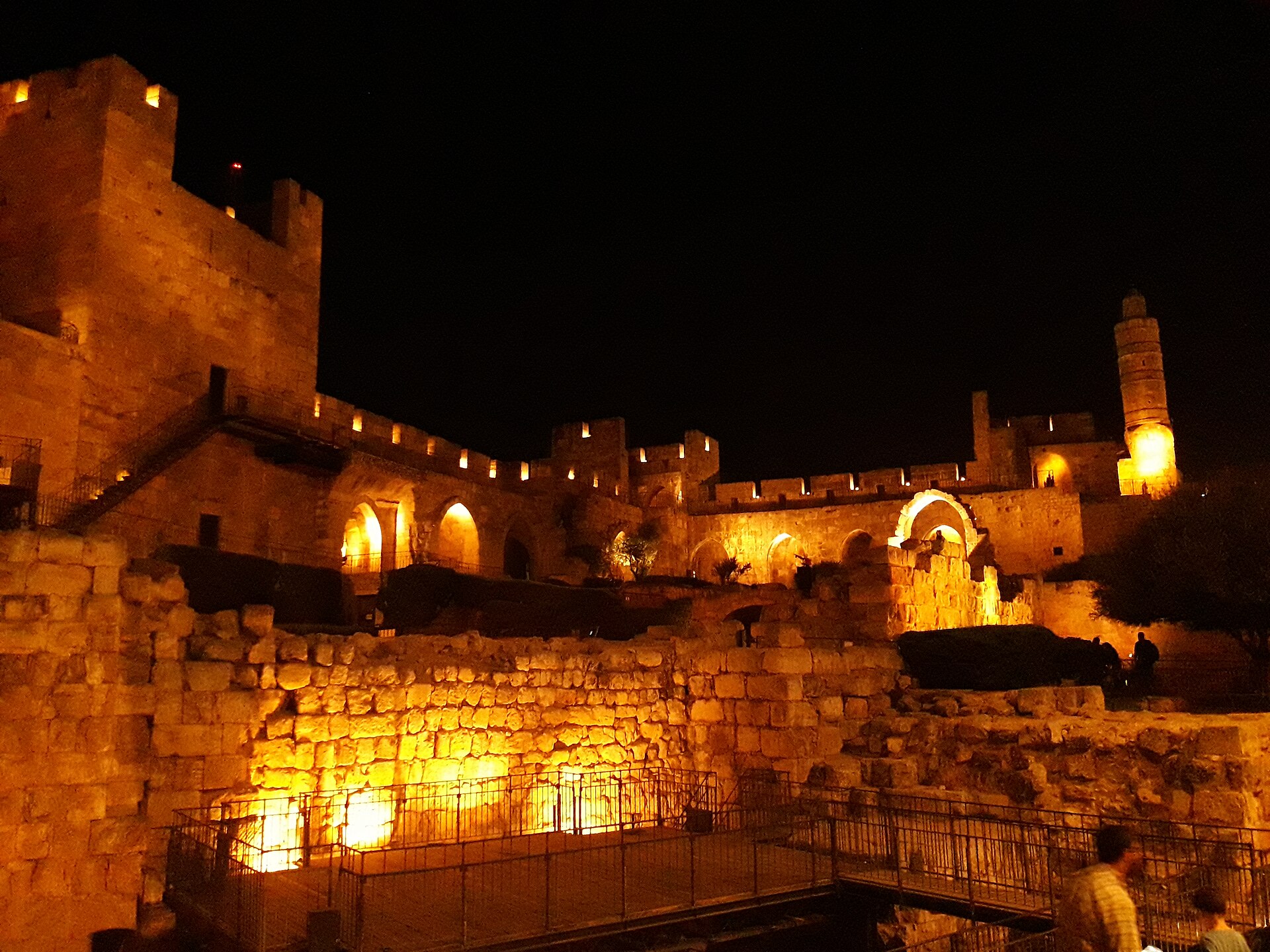 The Tower of David citadel's courtyard at night, its ancient walls, arches and minaret floodlit in warm light