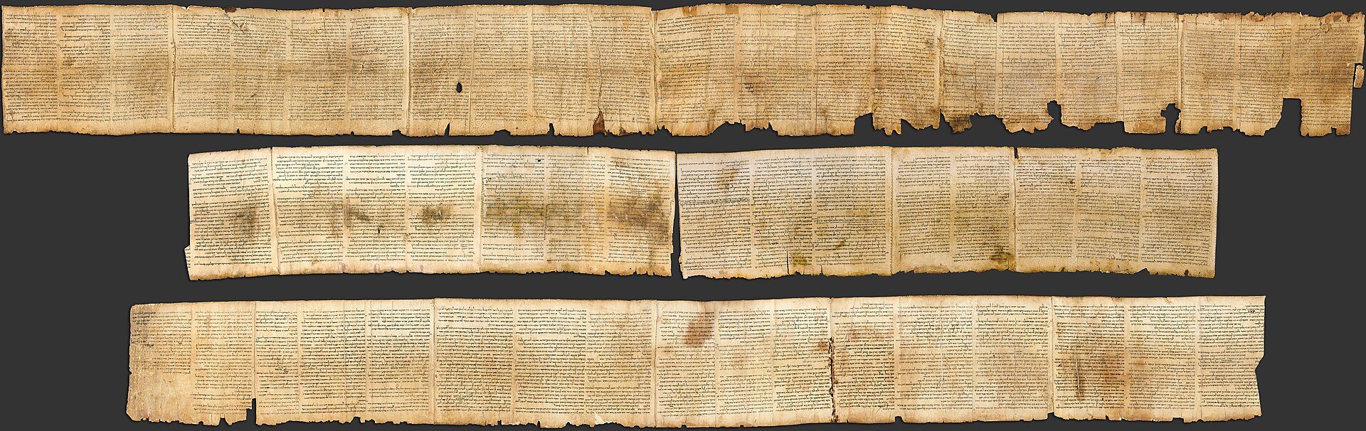 The whole Great Isaiah Scroll laid out in three rows against a dark background, its yellowed parchment sheets packed with columns of Hebrew text