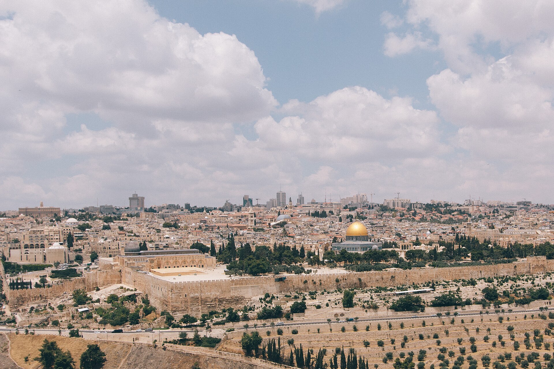 Wide view from the Mount of Olives over olive terraces to the Old City walls, Al-Aqsa Mosque and the golden Dome of the Rock under billowing clouds