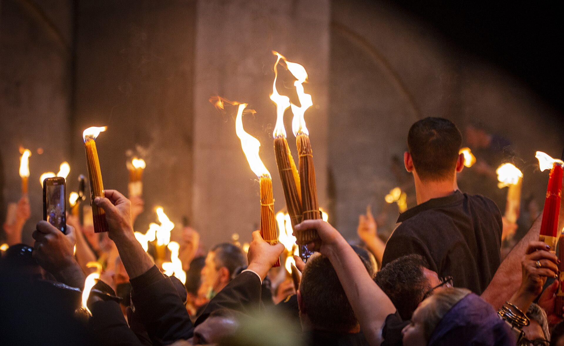 Worshippers raising blazing bundles of candles lit from the Holy Fire inside the Church of the Holy Sepulchre in Jerusalem on Orthodox Holy Saturday