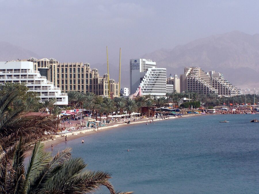 Eilat's North Beach lined with large hotels and palm trees on the Gulf of Aqaba, with bare mountains behind