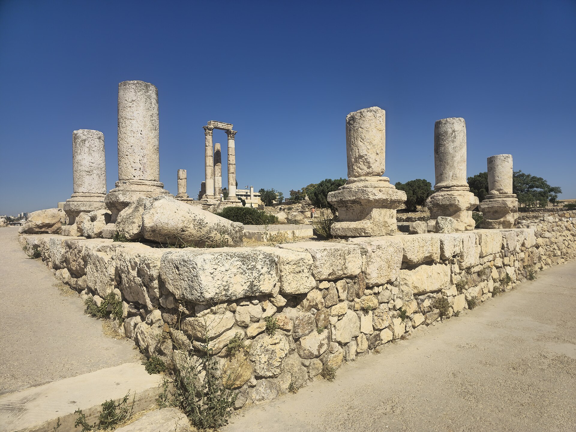 Tall weathered stone columns of a Roman temple on a raised platform at the Amman Citadel under a clear blue sky